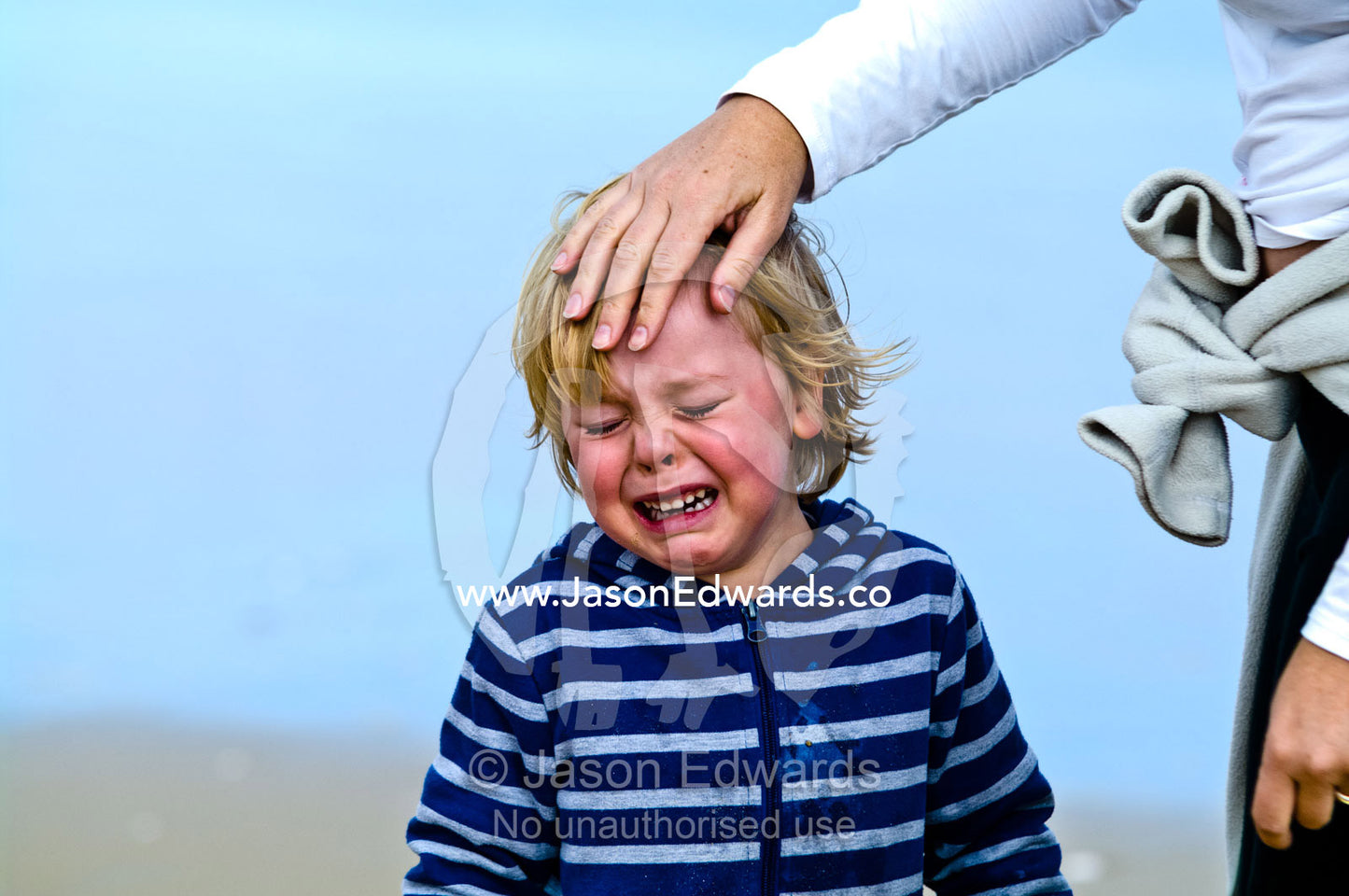 A mother comforts her crying son who hurt himself at the beach. Venus Bay, Bass Strait, South Gippsland, Victoria, Australia.