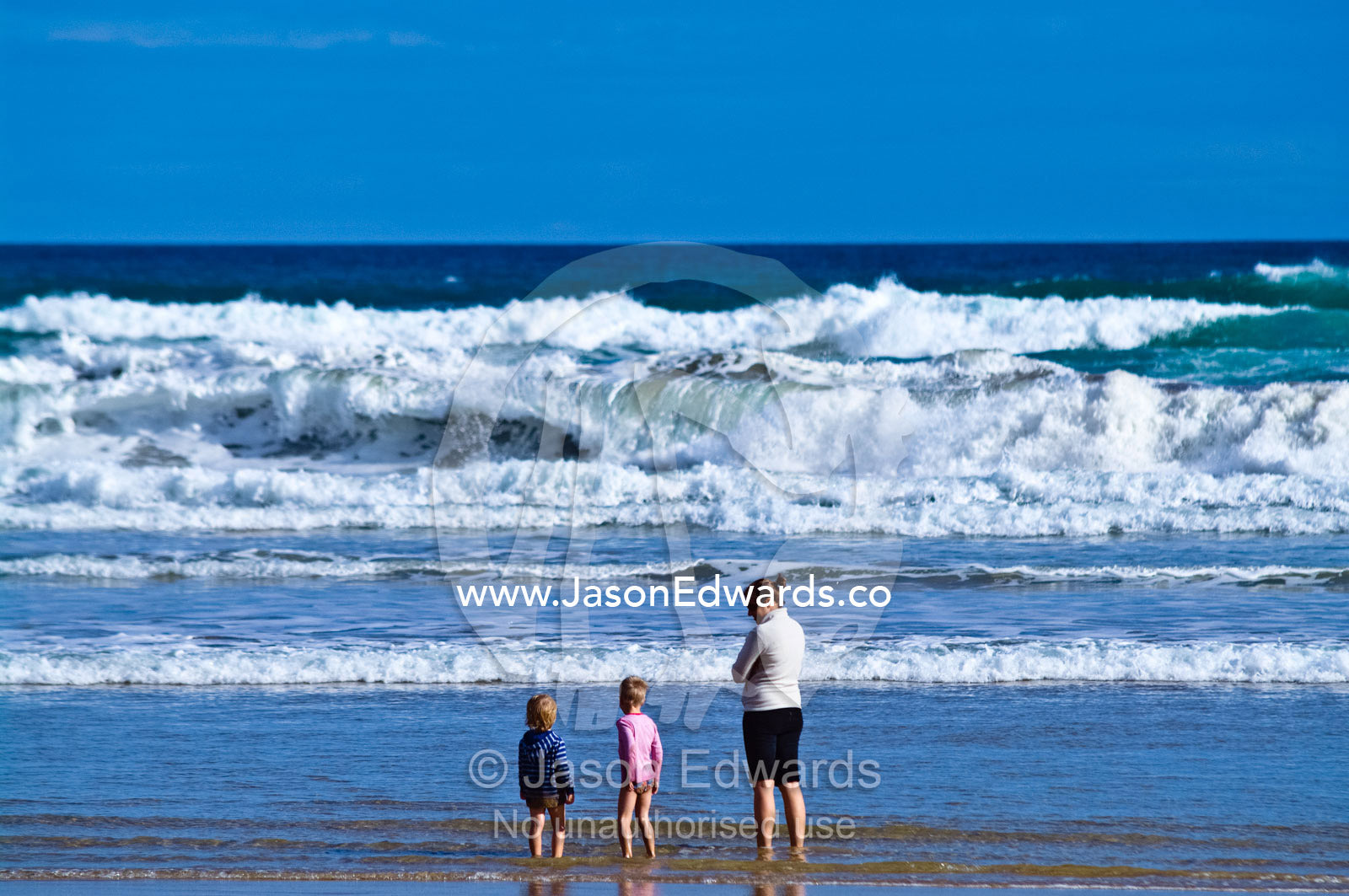A mother watches two boys playing on the beach near dangerous waves. Venus Bay, Bass Strait, South Gippsland, Victoria, Australia.