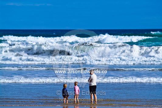 A mother watches two boys playing on the beach near dangerous waves. Venus Bay, Bass Strait, South Gippsland, Victoria, Australia.