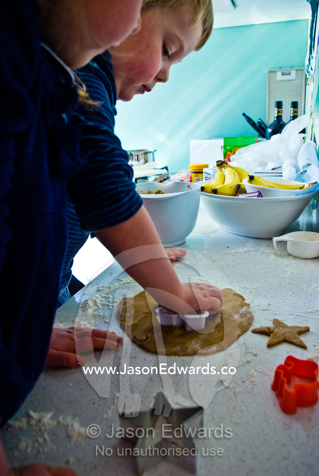 A young boy uses a cookie cutter to bake gingerbread men. Carlton North, Melbourne, Victoria, Australia.