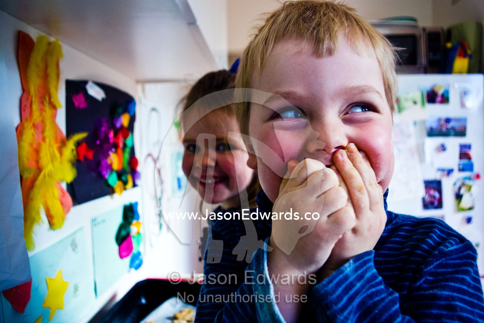 A cheeky boy caught stealing chocolate whilst baking gingerbread men. Carlton North, Melbourne, Victoria, Australia.