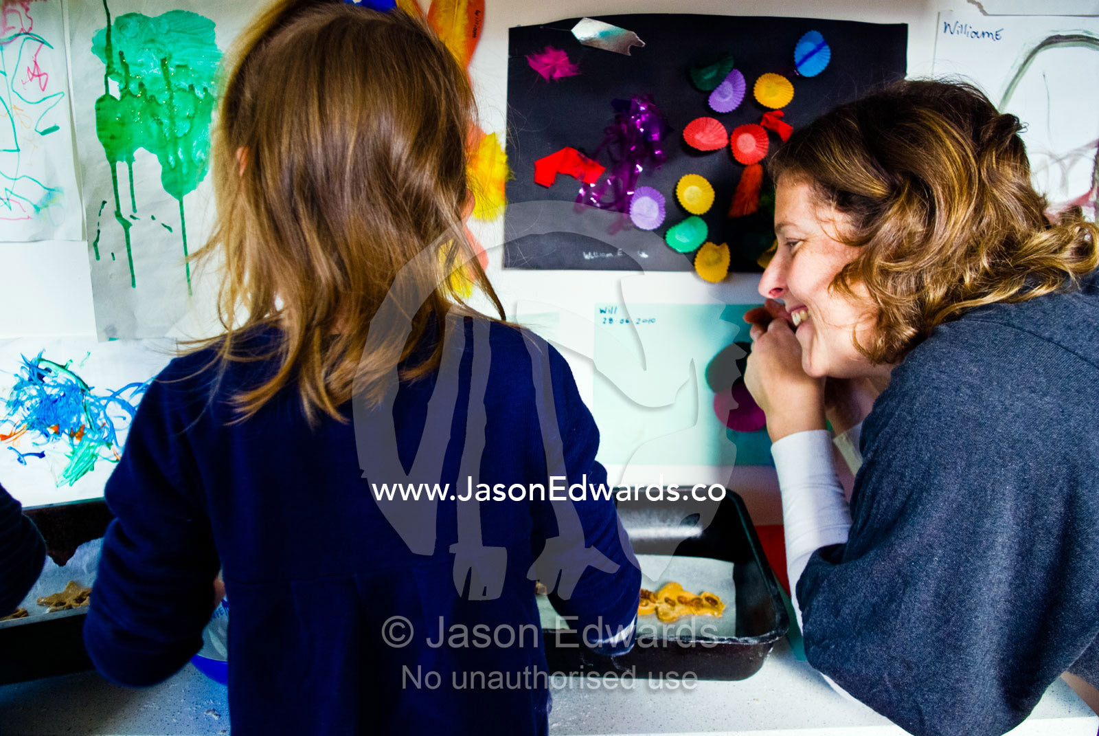 A mother helps children bake gingerbread men in a domestic kitchen. Carlton North, Melbourne, Victoria, Australia.