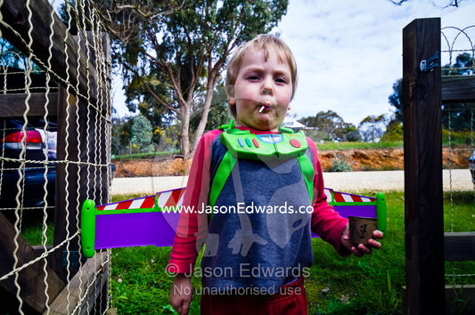 A boy proudly displays his costume wings sucking a lollypop. Castlemaine, Victoria, Australia.