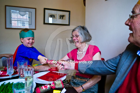 A young boy pops a Christmas bon bon at a family luncheon celebration. Carlton North, Melbourne, Victoria, Australia.
