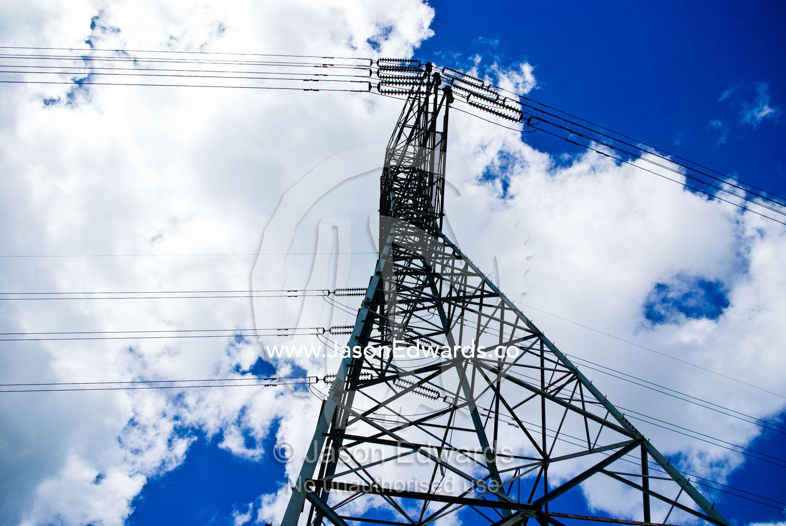 A steel high voltage electricity tower and cables rising into the sky. Gardener's Creek Trail, Malvern East, Melbourne, Victoria, Australia.
