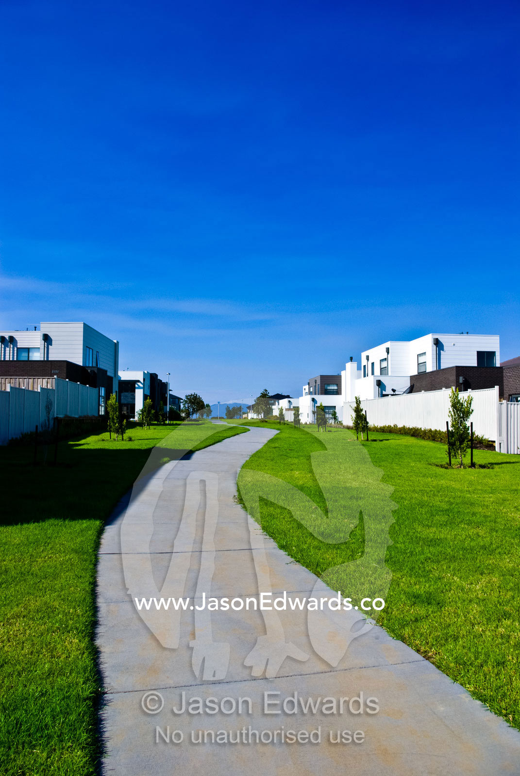 A pedestrian path through a linear park between new suburban homes. Waverley Park, Mulgrave, Melbourne, Victoria, Australia.