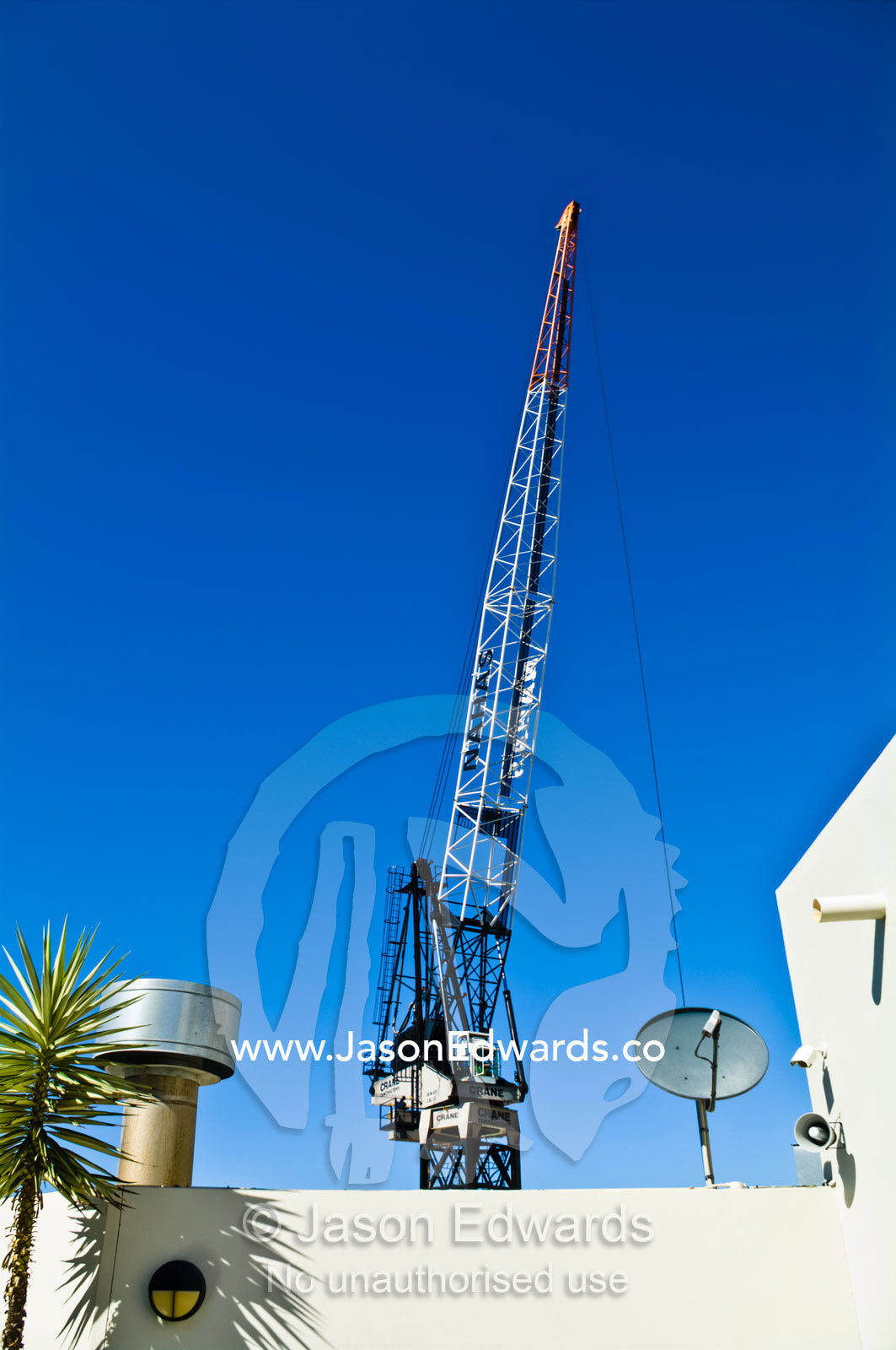 A construction crane gantry lowers a steel cable over a rooftop. Sydney, New South Wales, Australia.