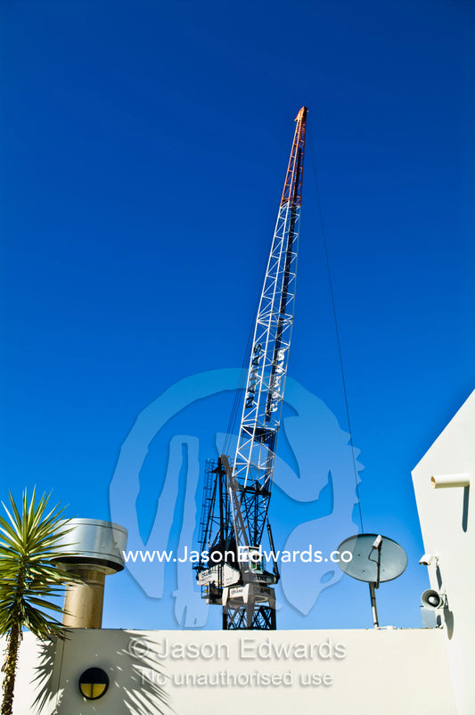 A construction crane gantry lowers a steel cable over a rooftop. Sydney, New South Wales, Australia.