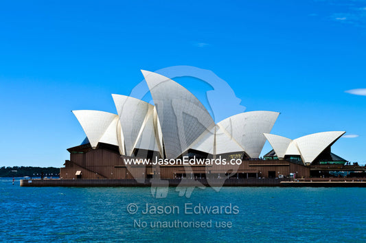 The sails of the Sydney Opera House billow beneath a blue summer sky. Bennelong Point, Sydney Harbour, Sydney Cove, Warrane, Port Jackson, Circular Quay, Sydney, New South Wales, Australia.