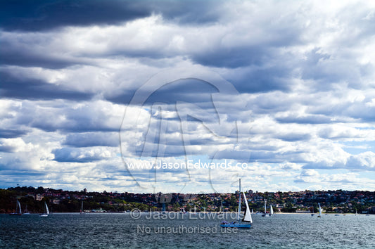 Summer storm clouds gather over racing yachts sailing in a regatta. Manly Cove, Manly, Sydney Harbour, Sydney, New South Wales, Australia.