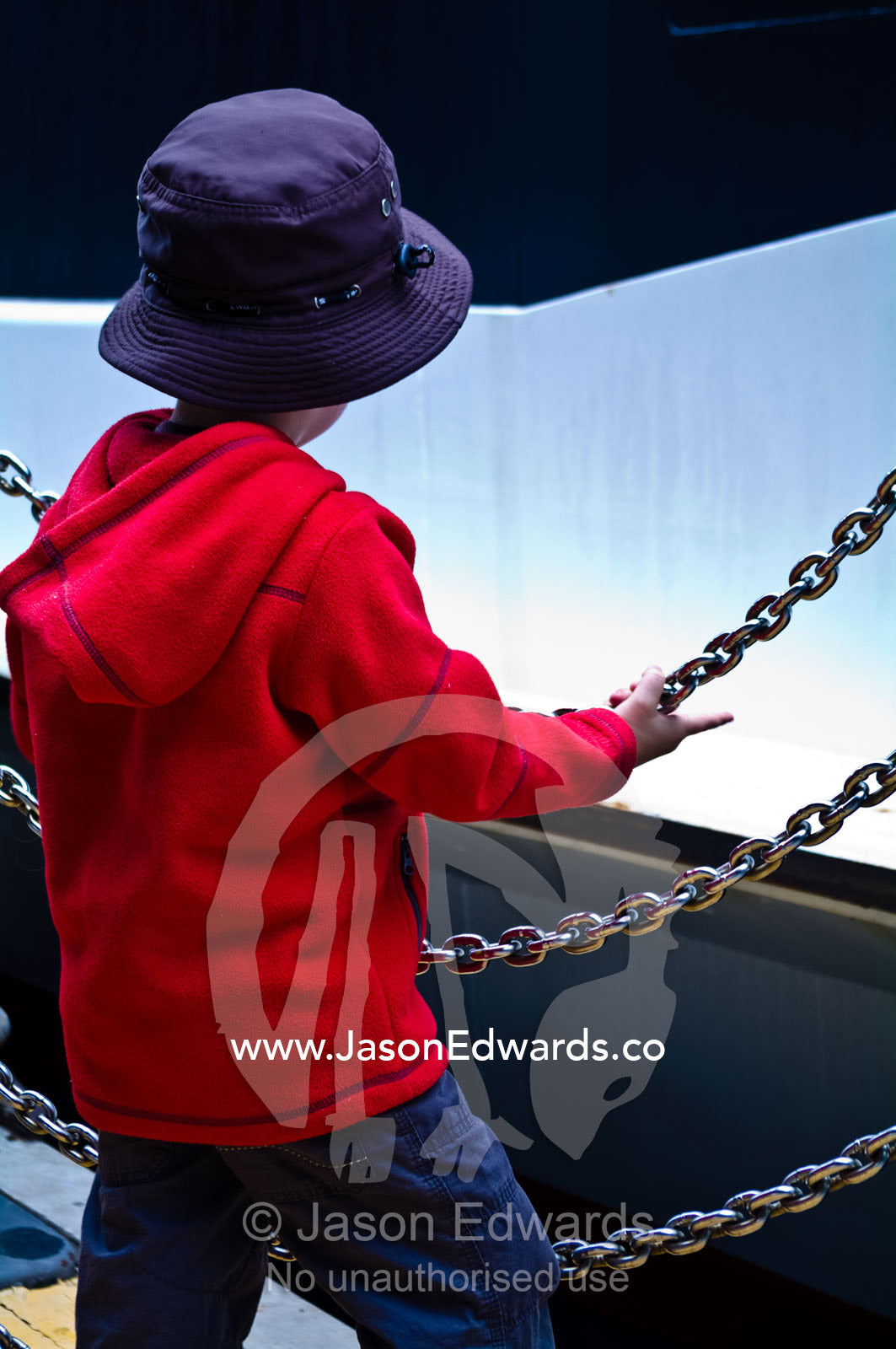 A young boy waits behind a chain fence to board a Sydney Harbour ferry Sydney Harbour, Sydney Cove, Warrane, Port Jackson, Circular Quay, Sydney, New South Wales, Australia.