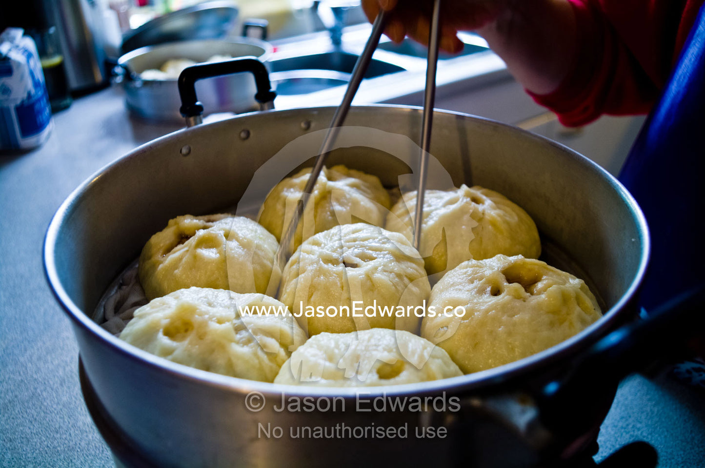 Steel chopsticks used to remove pork buns, baize, from a hot steamer. Campsie, Syndey, New South Wales, Australia.