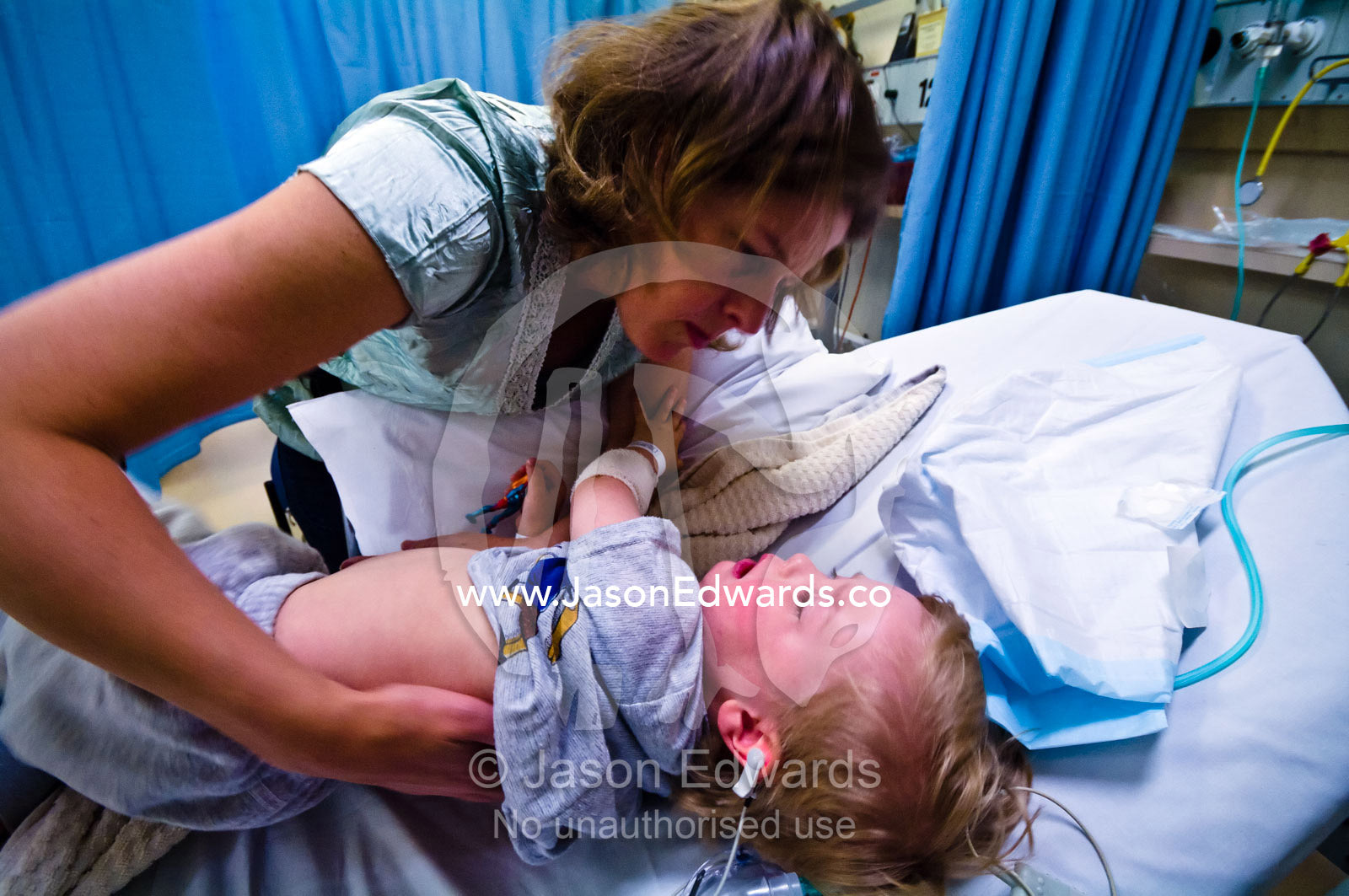 A mother comforts her distressed son in recovery after ear surgery. Epworth Freemasons Hospital, East Melbourne, Victoria, Australia.