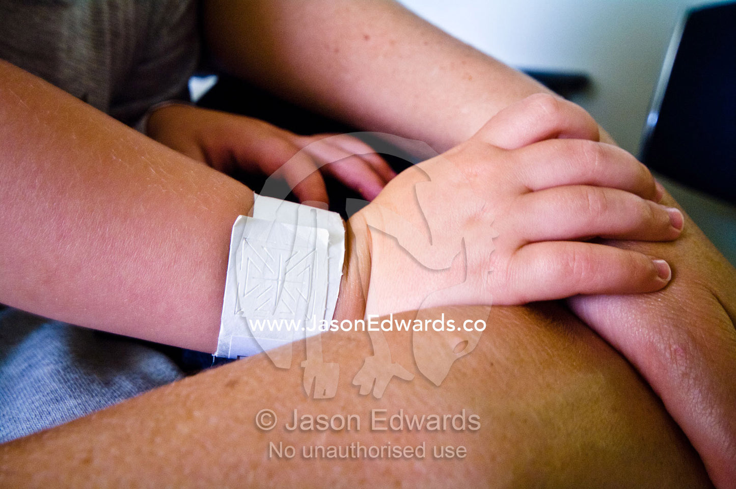 A boys small hand rests on his mother's arm for comfort after surgery. Epworth Freemasons Hospital, East Melbourne, Victoria, Australia.