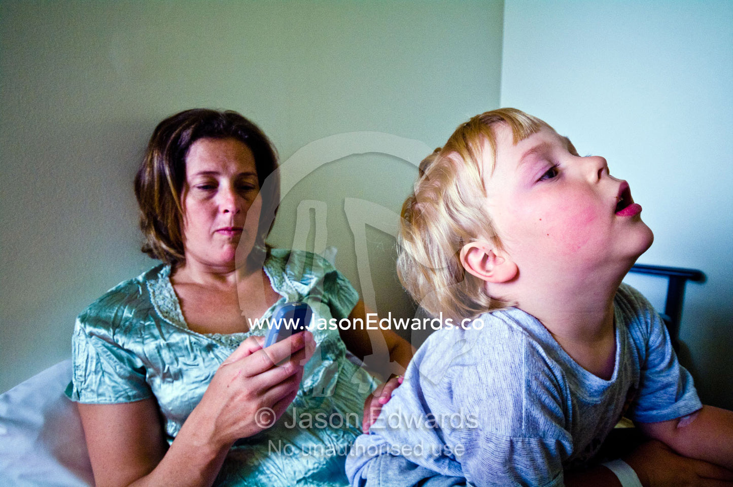 A mother sends a message on her cell phone in a hospital waiting room. Epworth Freemasons Hospital, East Melbourne, Victoria, Australia.