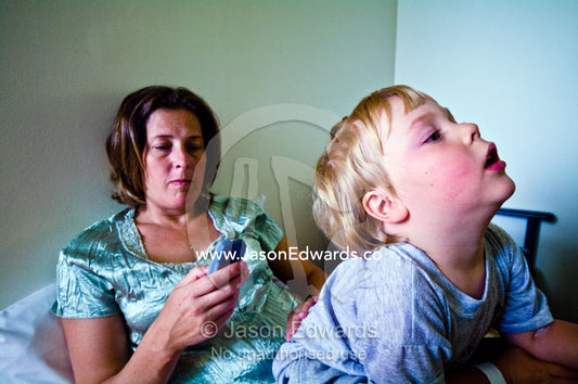 A mother sends a message on her cell phone in a hospital waiting room. Epworth Freemasons Hospital, East Melbourne, Victoria, Australia.