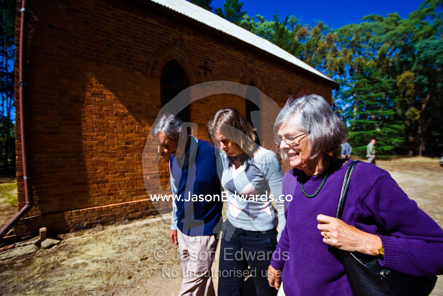 A daughter and her parents leave a Christmas morning church service. St Mary's Church, Elphinstone, Victoria, Australia.