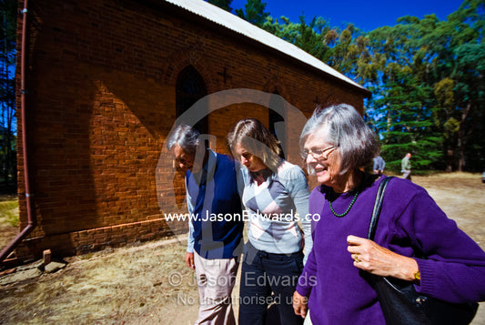 A daughter and her parents leave a Christmas morning church service. St Mary's Church, Elphinstone, Victoria, Australia.