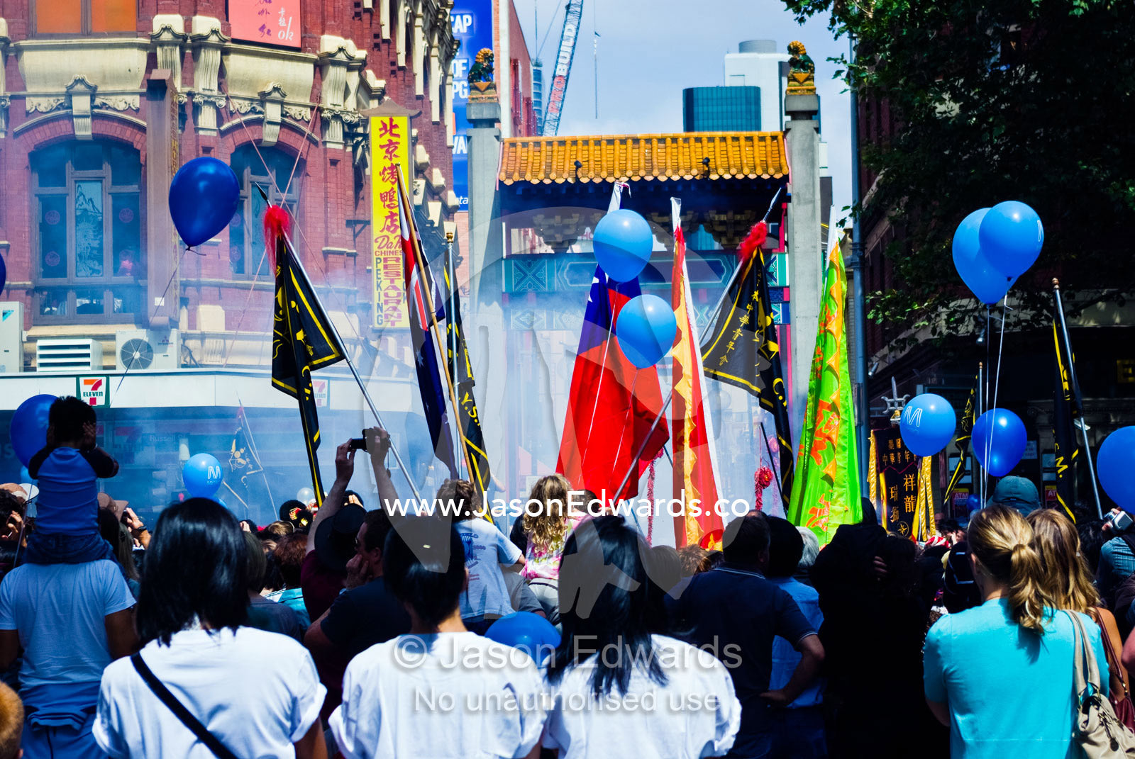 Crowds gather to celebrate Chinese New Year with fireworks and flags. Chinatown, Melbourne, Victoria, Australia.