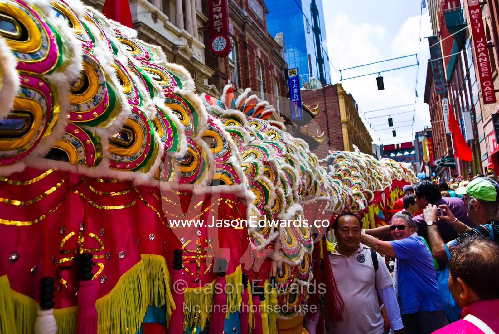 Crowds touch a ceremonial dragon for good luck at Chinese New Year. Chinatown, Melbourne, Victoria, Australia.
