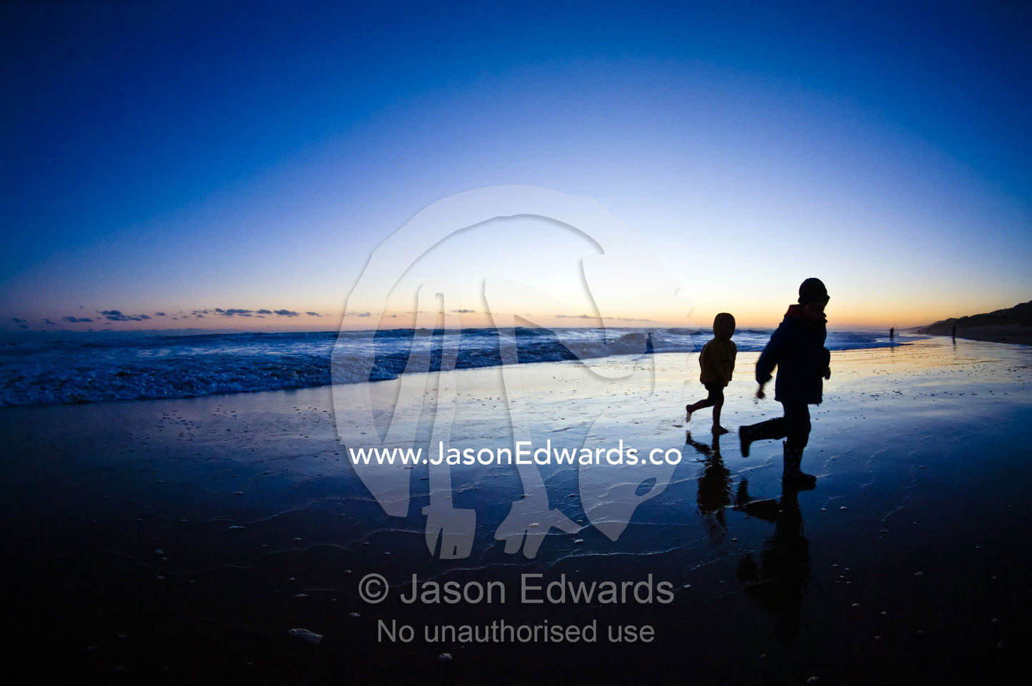 Small boys run from waves on a remote stretch of beach at twilight. Venus Bay, Cape Liptrap Coastal Park, Bass Strait, South Gippsland, Victoria, Australia.