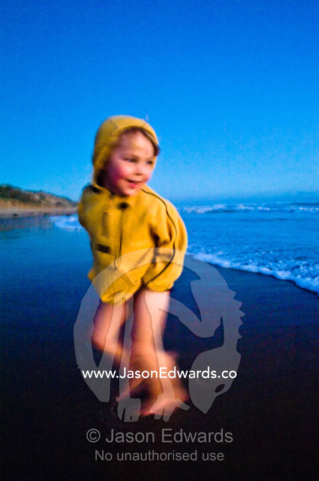 A small boy runs from waves on a remote stretch of beach at twilight. Venus Bay, Cape Liptrap Coastal Park, Bass Strait, South Gippsland, Victoria, Australia.