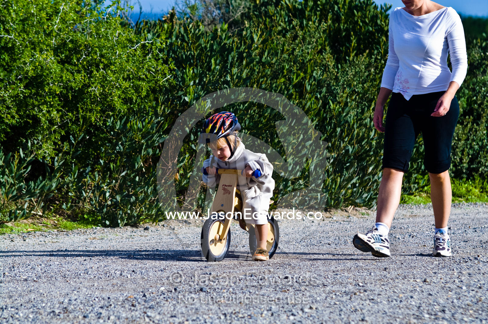 A young boy learns to ride a balance bike made from recycled timber. Venus Bay, Cape Liptrap Coastal Park, Bass Strait, South Gippsland, Victoria, Australia.