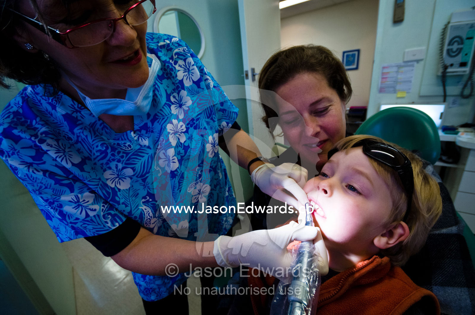 A dentist polishes a boy's teeth at his first dental check-up. East Melbourne, Melbourne, Victoria, Australia.