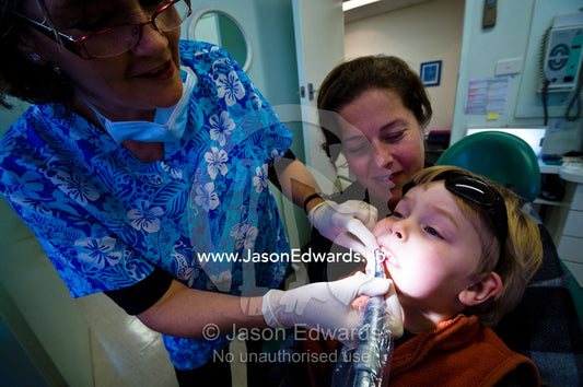 A dentist polishes a boy's teeth at his first dental check-up. East Melbourne, Melbourne, Victoria, Australia.