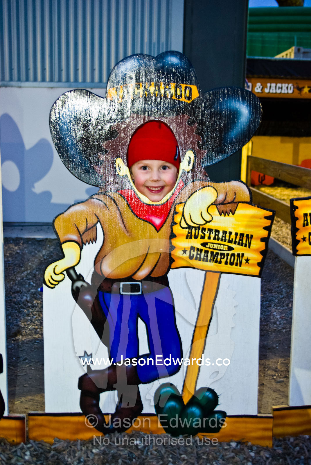 A small boy poses for a photo as a jackaroo in a fair side show. Royal Melbourne Agricultural Show, Flemington, Melbourne, Victoria, Australia.