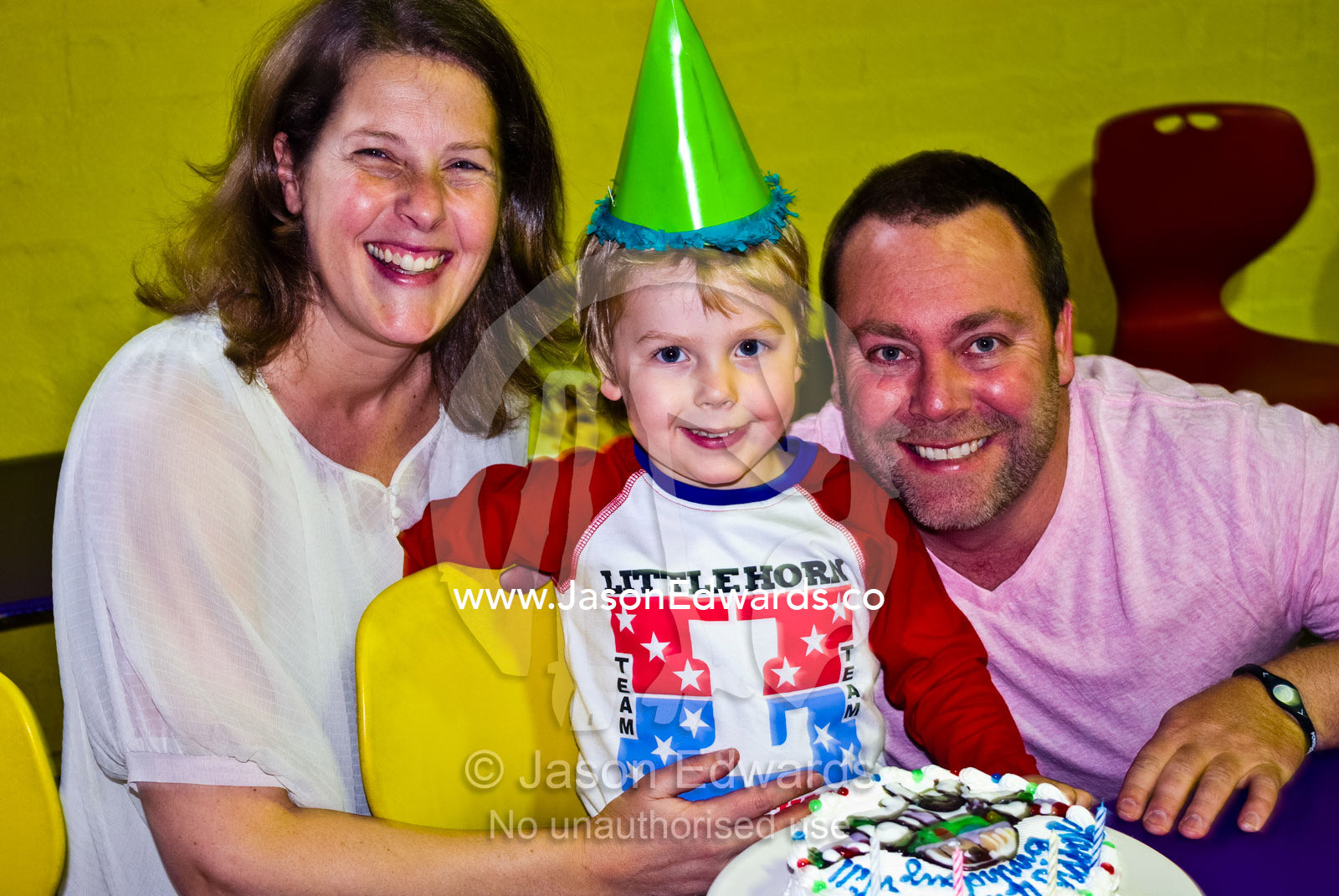 A happy family celebrates a boys fourth birthday party with a cake. Hawthorn, Melbourne, Victoria, Australia.