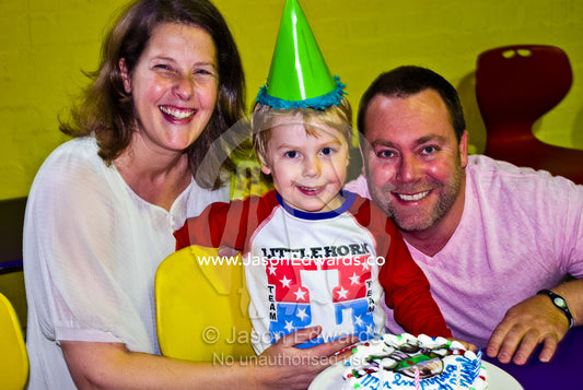 A happy family celebrates a boys fourth birthday party with a cake. Hawthorn, Melbourne, Victoria, Australia.