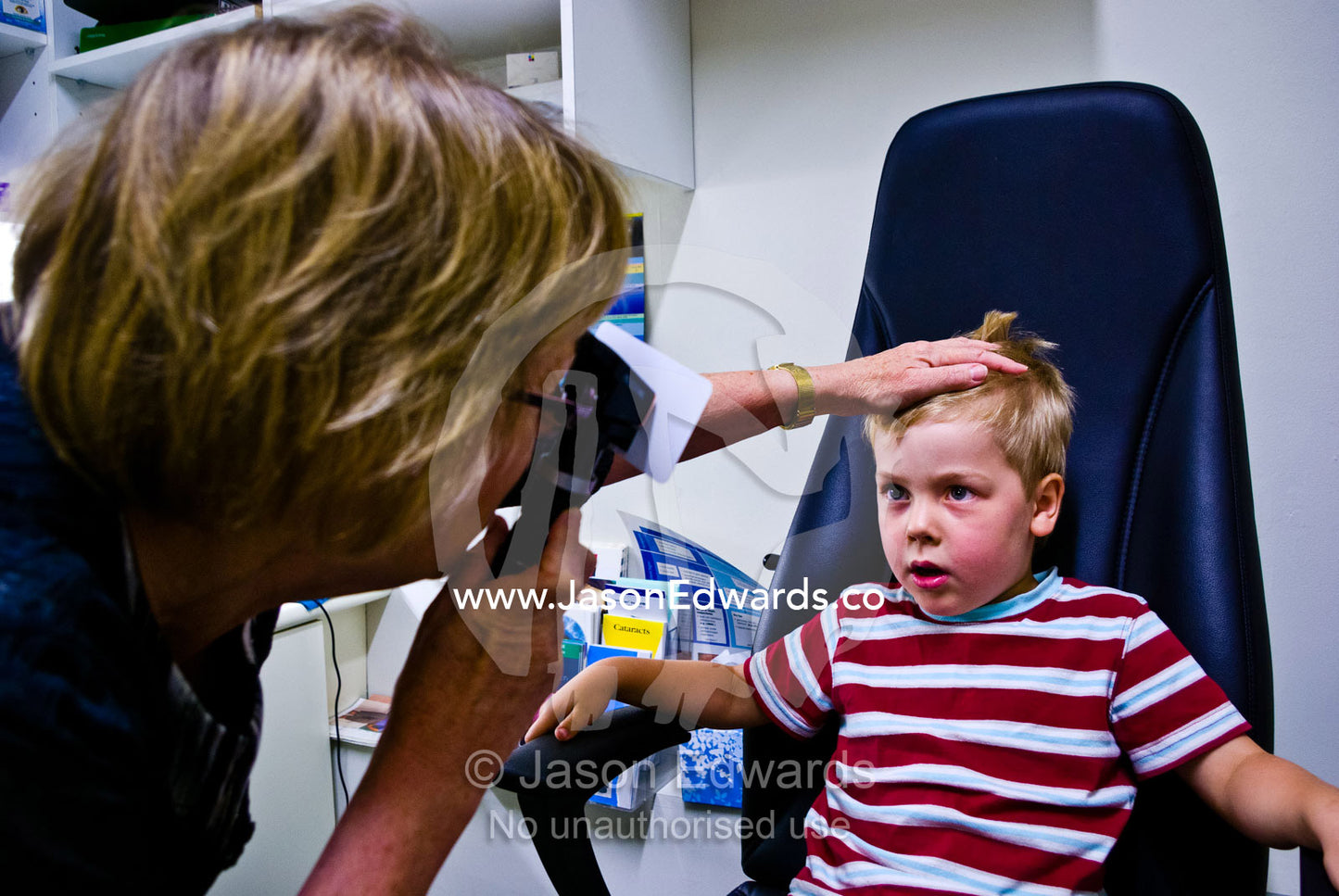 A children's optometrist gives a small boy his first eye examination. Hawthorn, Melbourne, Victoria, Australia.