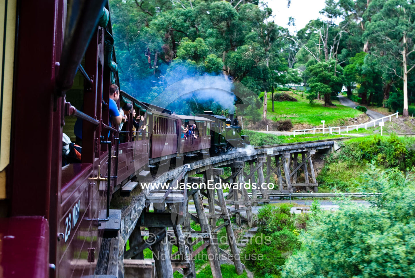 Passengers on an antique steam train crossing a wooden rail bridge. Belgrave, Melbourne, Victoria, Australia.