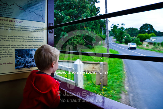 A small boy looks from the carriage window of an antique steam train. Belgrave, Melbourne, Victoria, Australia.