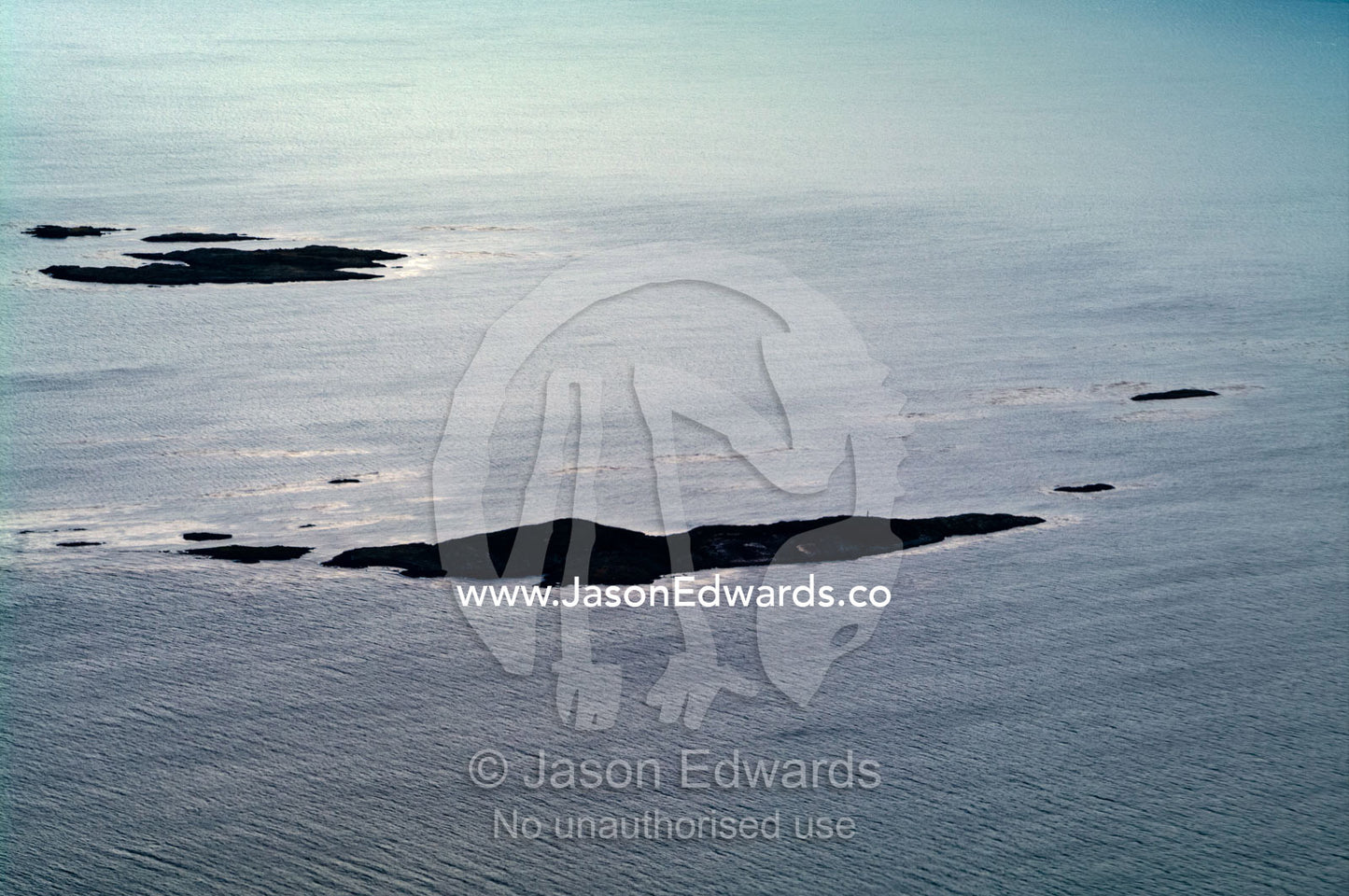 Small barren rocky islands are shipping hazards in a vast ocean bay. Ushuaia Bay, The Beagle Channel, Tierra del Fuego Archipelago, Straits of Magellan, Ushuaia, Tierra del Fuego Province, Patagonia, Argentina.