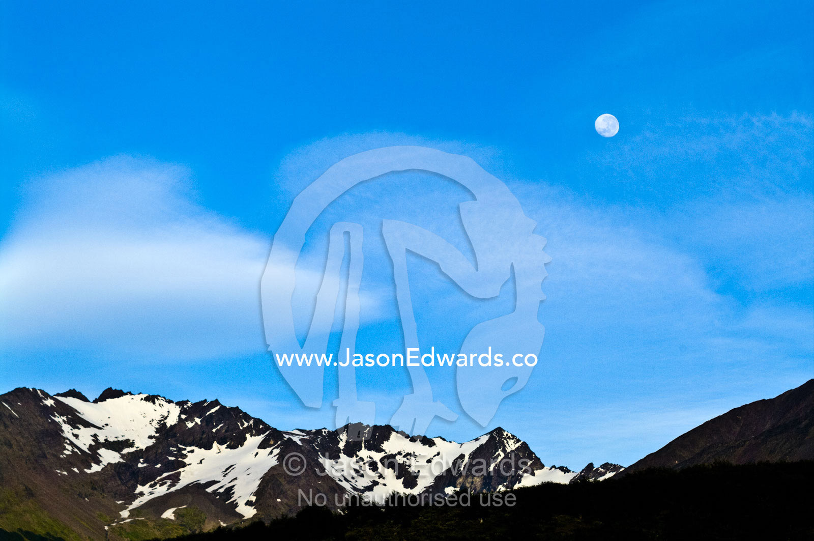 Moonrise in a clear blue sky over snowcapped Andean peaks and ridges. Ushuaia, Martial Mountains, Fuegian Andes, Ushuaia Bay, The Beagle Channel, Tierra del Fuego Archipelago, Straits of Magellan, Tierra del Fuego Province, Patagonia, Argentina.