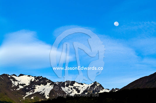 Moonrise in a clear blue sky over snowcapped Andean peaks and ridges. Ushuaia, Martial Mountains, Fuegian Andes, Ushuaia Bay, The Beagle Channel, Tierra del Fuego Archipelago, Straits of Magellan, Tierra del Fuego Province, Patagonia, Argentina.
