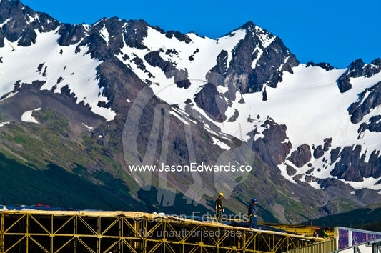 Workers construct the steel frame of a new casino below snowy peaks. Ushuaia, Martial Mountains, Fuegian Andes, Ushuaia Bay, The Beagle Channel, Tierra del Fuego Archipelago, Straits of Magellan, Tierra del Fuego Province, Patagonia, Argentina.
