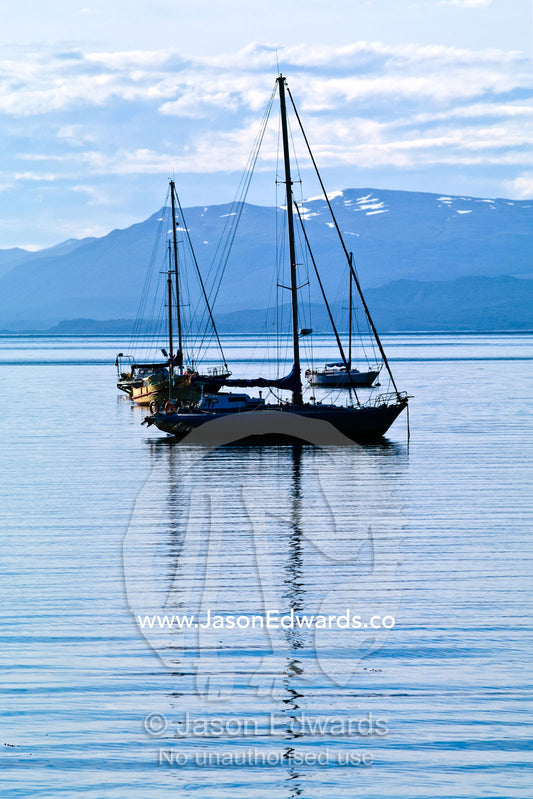 A small yacht rests in the calm, sheltered bay of the port at Ushuaia. Ushuaia, Martial Mountains, Fuegian Andes, Ushuaia Bay, The Beagle Channel, Tierra del Fuego Archipelago, Straits of Magellan, Tierra del Fuego Province, Patagonia, Argentina.