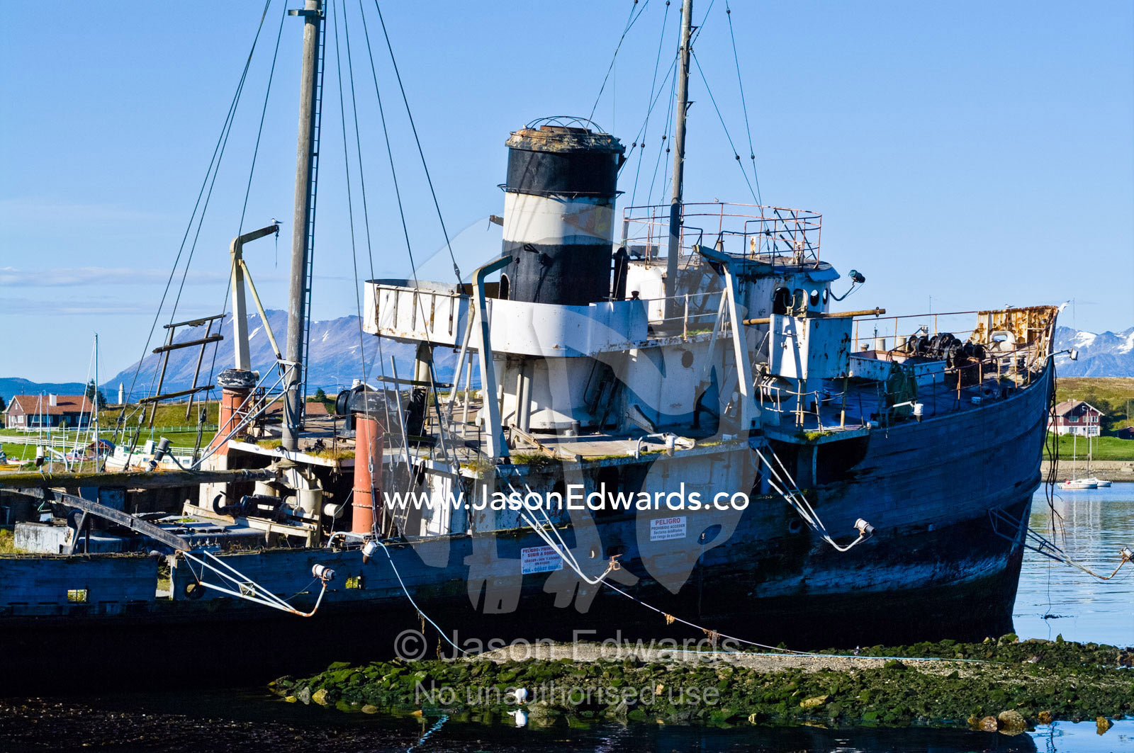 A tugboats shipwreck rests in the shallows of a sheltered bay. Ushuaia, The Beagle Channel, Ushuaia Bay, Tierra del Fuego Archipelago, Straits of Magellan, Tierra del Fuego Province, Patagonia, Argentina.