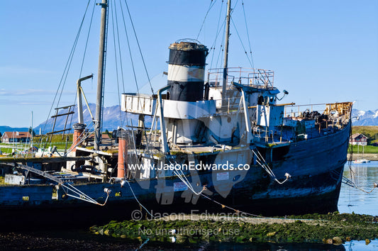 A tugboats shipwreck rests in the shallows of a sheltered bay. Ushuaia, The Beagle Channel, Ushuaia Bay, Tierra del Fuego Archipelago, Straits of Magellan, Tierra del Fuego Province, Patagonia, Argentina.