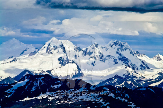 Snow and ice covered mountain peaks dappled in patches of sunlight. Ushuaia, Martial Mountains, Fuegian Andes, Tierra del Fuego Archipelago, Straits of Magellan, Tierra del Fuego Province, Patagonia, Argentina.