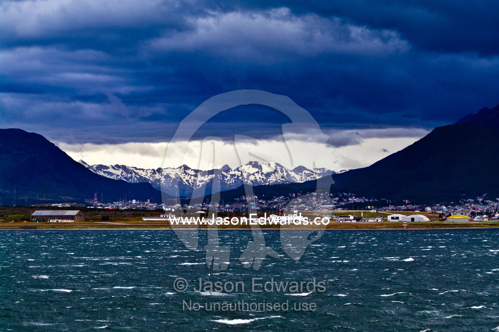 Strong wind whips whitecaps across the ocean surface beneath a storm. Ushuaia, Martial Mountains, Fuegian Andes, Ushuaia Bay, The Beagle Channel, Tierra del Fuego Archipelago, Straits of Magellan, Tierra del Fuego Province, Patagonia, Argentina.