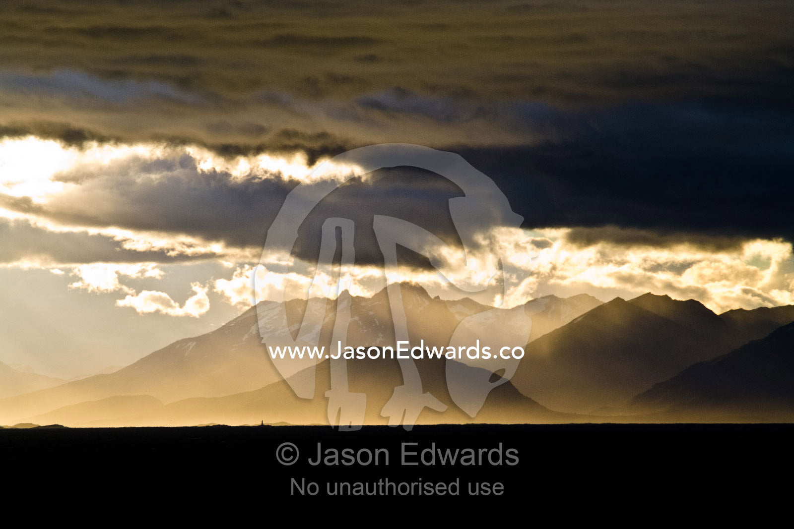 A sunset storm over the Andes turns sea mist and clouds golden. Ushuaia, Martial Mountains, Fuegian Andes, Ushuaia Bay, The Beagle Channel, Tierra del Fuego Archipelago, Straits of Magellan, Tierra del Fuego Province, Patagonia, Argentina.