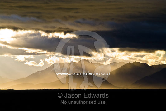 A sunset storm over the Andes turns sea mist and clouds golden. Ushuaia, Martial Mountains, Fuegian Andes, Ushuaia Bay, The Beagle Channel, Tierra del Fuego Archipelago, Straits of Magellan, Tierra del Fuego Province, Patagonia, Argentina.