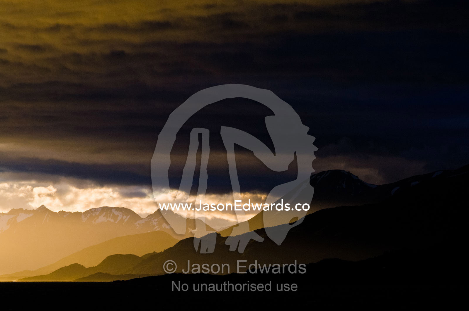 Sun rays pierce a dark menacing storm bank over the Andes mountains. Ushuaia, Martial Mountains, Fuegian Andes, Ushuaia Bay, The Beagle Channel, Tierra del Fuego Archipelago, Straits of Magellan, Tierra del Fuego Province, Patagonia, Argentina.