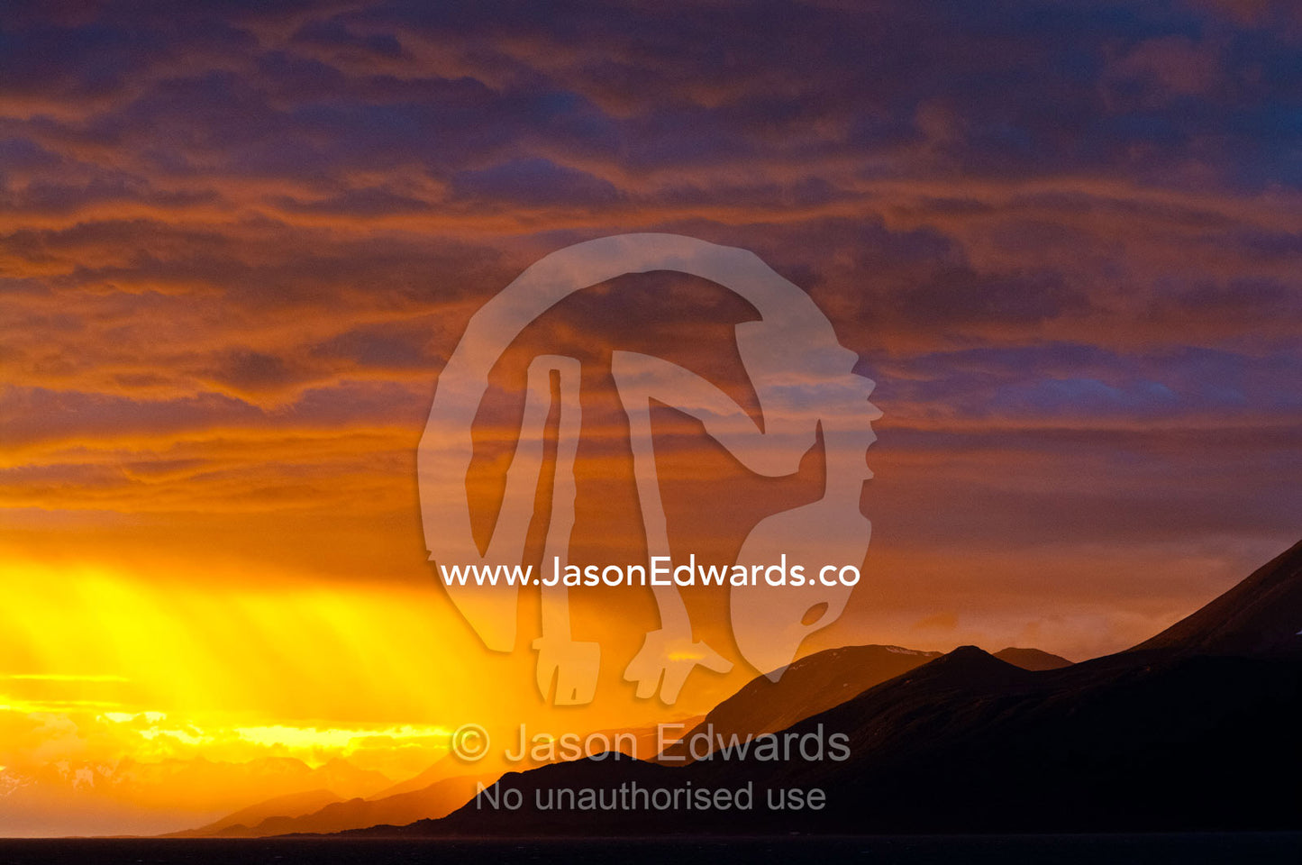 The setting sun turns a rain storm over the Andes fiery golden. Ushuaia, Martial Mountains, Fuegian Andes, Ushuaia Bay, The Beagle Channel, Tierra del Fuego Archipelago, Straits of Magellan, Tierra del Fuego Province, Patagonia, Argentina.