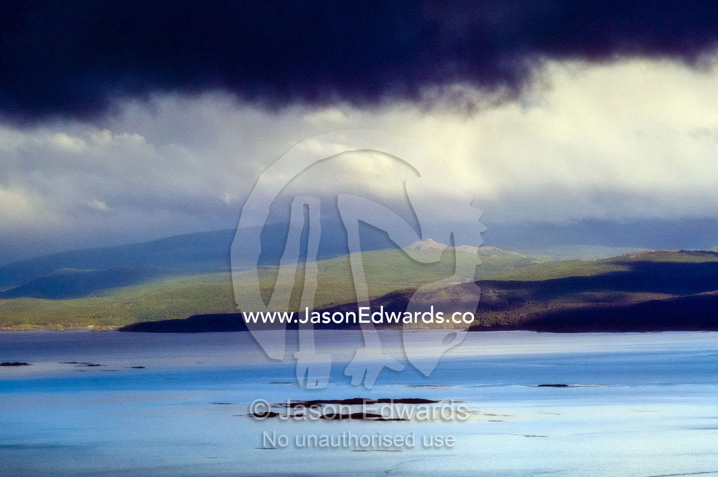 A storm front descends from the Andes Mountains over a turquoise sea. Ushuaia Bay, The Beagle Channel, Fuegian Andes, Tierra del Fuego Archipelago, Straits of Magellan, Ushuaia, Tierra del Fuego Province, Patagonia, Argentina.