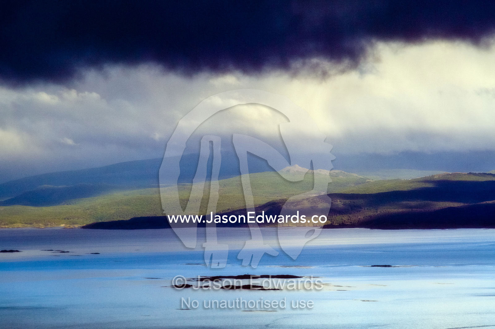 A storm front descends from the Andes Mountains over a turquoise sea. Ushuaia Bay, The Beagle Channel, Fuegian Andes, Tierra del Fuego Archipelago, Straits of Magellan, Ushuaia, Tierra del Fuego Province, Patagonia, Argentina.